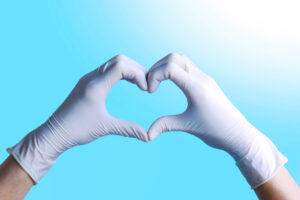 Doctor's,Hands,In,Protective,Gloves,Making,Heart,Shape,On,Blue