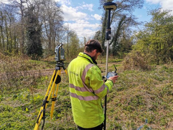 surveyor reading measurement on survey instrument in wooded area